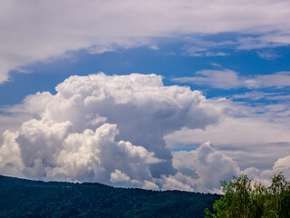 Massive rain clouds, cumulus congestus and cumulonimbus, in the distance above the top of the hill
