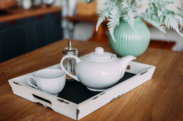 White cup and teapot on a tray. Home comfort concept.