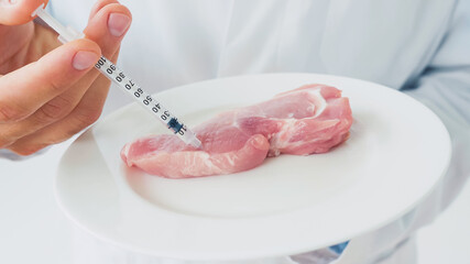 Cropped view of scientist injecting raw piece of beef on plate