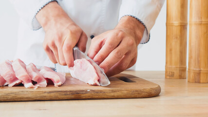 Obraz na płótnie Canvas partial view of chef slicing pork tenderloin on chopping board on white