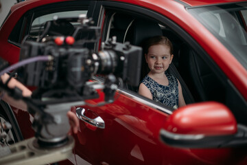 Professional actress girl works in the frame on the set. Shooting with a car on a large white...