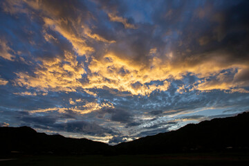 mountain scenery silhouette blue sky Yellow-orange clouds after sunset and after rain, evening. Beautiful evening sky image for the blue background.