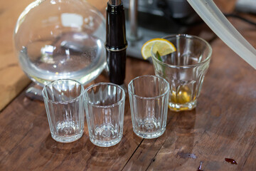 selective focus, small clear glass of water, placed on a wooden table, coffee shop, drink
