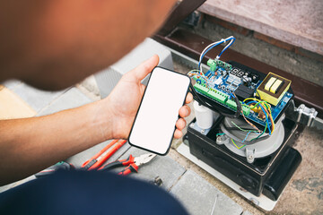 Technician man installing and checking the function of automatic gate and holds the phone with...