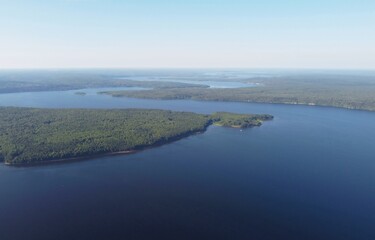 A wide river winds and goes into the distance against the background of the forest. Photo from the drone