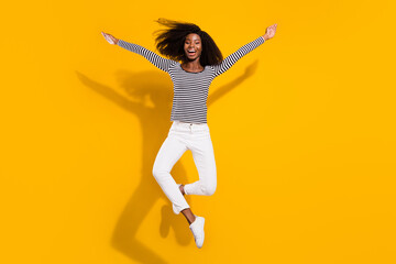 Fototapeta na wymiar Full length body size photo woman jumping up laughing careless in striped shirt isolated vibrant yellow color background
