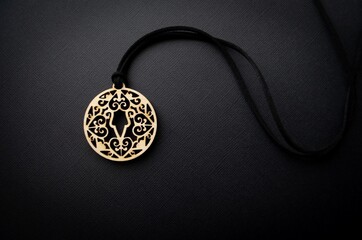 Yakut female amulet made of wood on a black background. Wooden traditional talisman. Boho style - obrazy, fototapety, plakaty