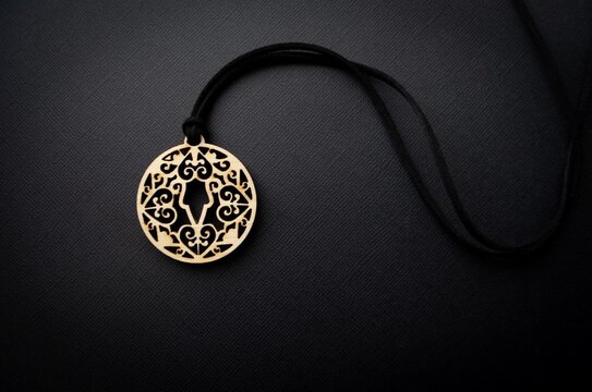 Yakut female amulet made of wood on a black background. Wooden traditional talisman. Boho style