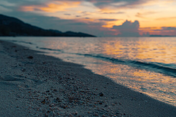 Tropical sandy beach at sunset. Colorful sky and reflections in water. Close up sand and stones.