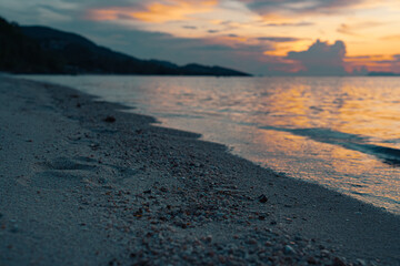 Tropical sandy beach at sunset. Colorful sky and reflections in water. Close up sand and stones.