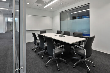 Interior view of office business conference room with black office chairs and large white table