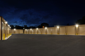 Large lit industrial storage warehouse complex with brown warehouse buildings at night