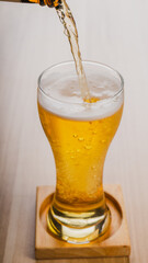 filling glass glasses of light beer, cold craft beer in a glass on wood table