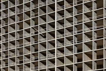 The light or bright grey background or backdrop of new concrete building construction in the rays of midday sun with many lines, squares, rhombs,triangles and rectangles