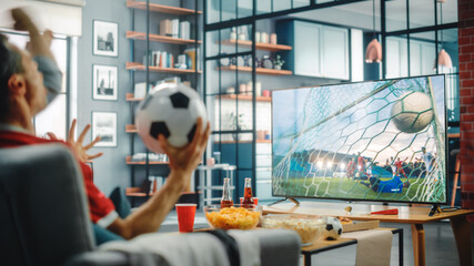 At Home Soccer Fans Sitting on a Couch Watch Football Game on TV, Cheer for Favourtite Sports Team...