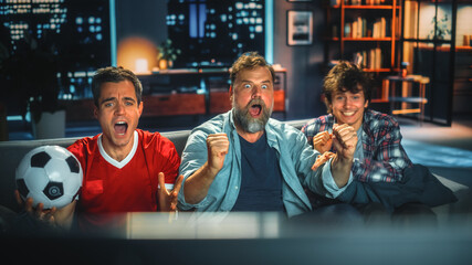 Night At Home: Three Joyful Soccer Fans Sitting on a Couch Watch Game on TV, Worry and Celebrate...