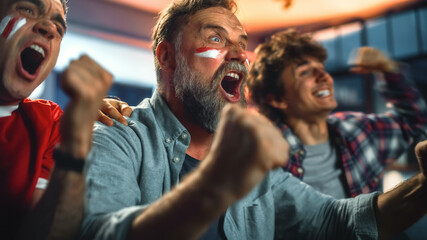 At Home Three Joyfuls Sports Fans with Painted Faces Sitting on a Couch Watch Game on TV, Celebrate Victory when Sports Team Wins Championship. Friends Cheer, Shout. Portrait Shot
