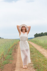 Fototapeta na wymiar Girl in a white dress and hat on a field background.