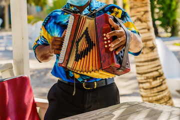 Dominican Republic. The beach musician plays the accordion. Hand plays accordions close-up. Accordionist. Dominican people. - obrazy, fototapety, plakaty
