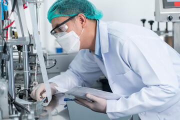 Male specialists wearing hair hoods and masks inspect the machineries, producing quality control...
