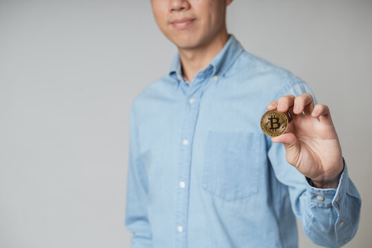 Happy young investor man with business shirt hold, show gold Bitcoin cryptocurrency on white background, Bitcoin cryptocurrency is future payment, trade as digital money, asset on online block chain.