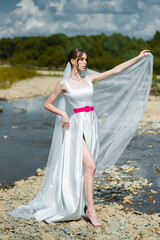 Fototapeta na wymiar Fashion bride posing on mountain river. Wedding day