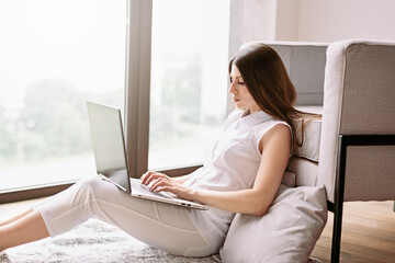 working young business woman from home sitting on floor with laptop. Work from home at cozy atmosphere concept while in quarantine isolation during the Covid-19 health crisis. creative professional