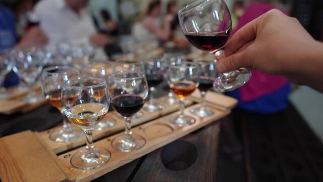 Winery Tasting Room. Wine Tasting Event. Tasters taste the wine. Swirling a glass of port wine. Samples of white, pink and red wine in glasses on a wooden tray