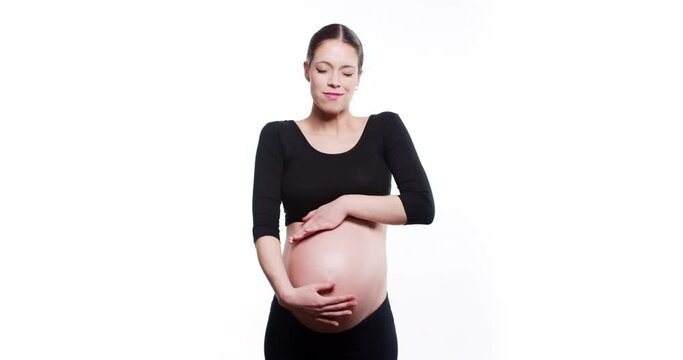 Happy young and fit pregnant woman gently smile and soft strokes her tummy while waiting for a baby, isolated on white background. Happy, healthy and touching pregnancy soulful moments concept