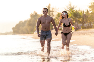 Happy romantic lover couple run and enjoy at the beach with sunset gold lighting. - summer vacation on sea beach concept