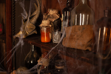 Halloween background Shelves with alchemy tools Skull spiderweb bottle with poison candles