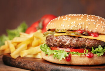 hamburger with French fries and vegetables on wooden table