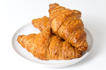 Plate with three tasty croissants on white background. French food