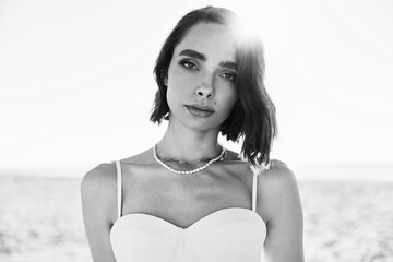 black and white portrait photo  beautiful girl with short hair looking in front in a white dress at the sunset - 443837512