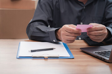 Postal man use paper note mark for address detail on box and use laptop computer check order list : Online order concept