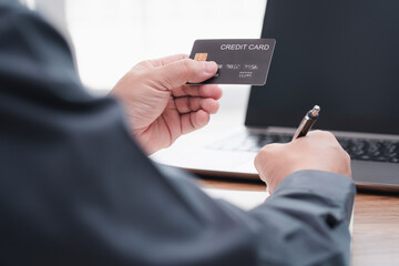 Businessman make online banking, making a payment or purchasing on the internet entering his credit card details on a smartphone and use laptop working on table