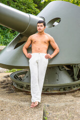 Young Man standing on a big gun, relaxing and thinking.