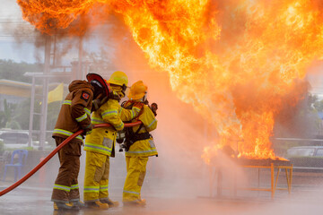 firefighter training., fireman using water and extinguisher to fighting with fire flame in an...