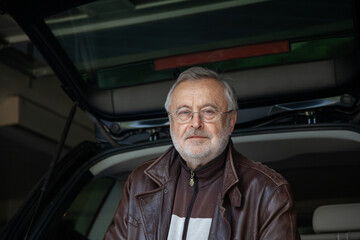 Handsome elderly man in glasses and leather jacket close-up