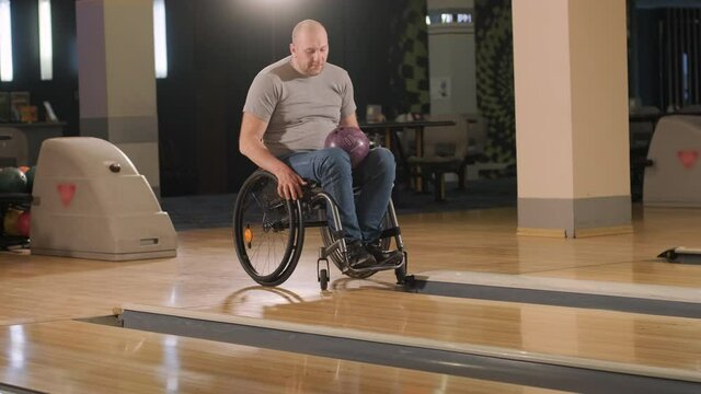 Two young disabled men in wheelchairs playing bowling in the club