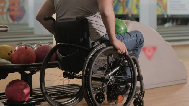 Two young disabled men in wheelchairs playing bowling in the club