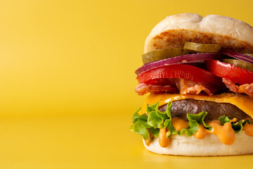 Beef burger with cheese and bacon on yellow background. Copy space