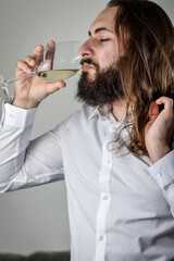 profile portrait of a young middle eastern businessman with beard and long hair drinking a glass of fresh white wine