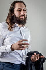 Portrait of a young middle eastern businessman with beard and long hair holding a glass of white...