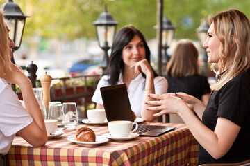 Beautiful women workers or students using laptop at cafe and talking