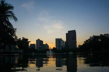 Fototapeta na wymiar Silhouette sunset sky in Bangkok city building with tree park