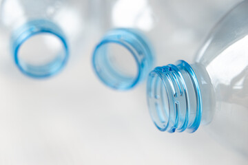 Transparent plastic bottles, on a clear surface. Transparent bottle neck. Recycling and disposal of single-use plastics. 
