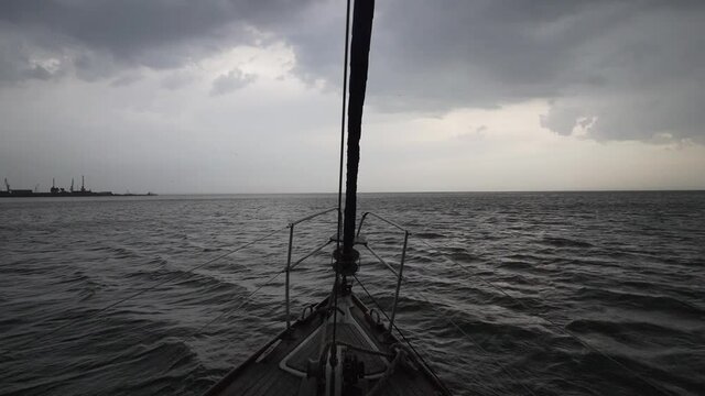 Deck of yacht in cloudy weather. The boat sails on the gray sea with waves.