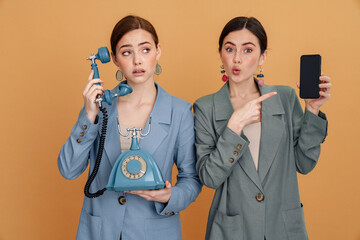 Young two women posing with retro phone and smartphone