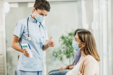 Fototapeta premium Nurse Measuring Temperature In Waiting Room